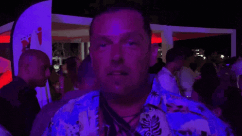 a man in a hawaiian shirt looks at the camera