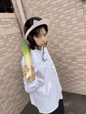 a young girl wearing a helmet and holding a large vegetable