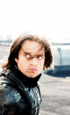 a man with long hair is wearing a black jacket and a black turtleneck