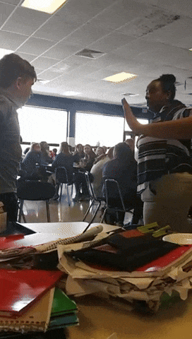 a group of people are sitting at tables in a classroom