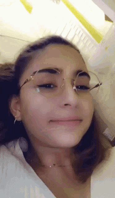 a girl wearing glasses and earrings is making a funny face .