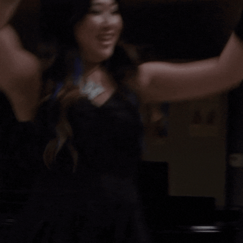 a woman with her arms in the air is smiling and laughing