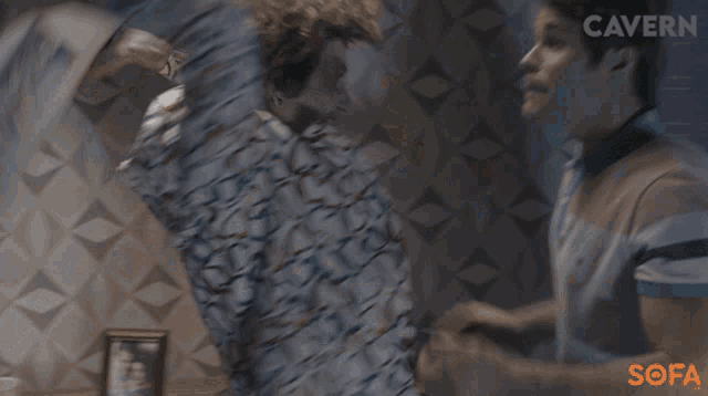 two men are fighting in front of a wall that has the word cavern on it