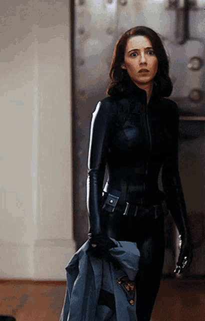 a woman in a black leather suit holding a jacket