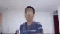 a blurry picture of a man in a blue shirt standing in front of a wall .