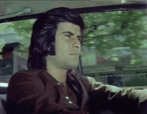 a man in a brown jacket is driving a car