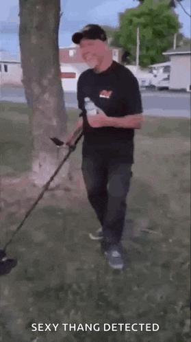 a man is holding a bottle of water and a metal detector in a park .