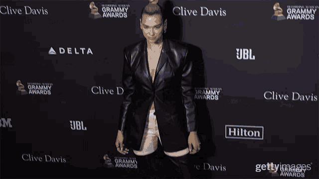 a woman standing in front of a wall that says clive davis on it