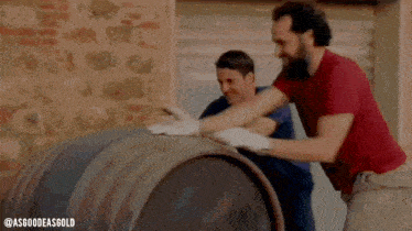 two men are carrying a large barrel in a winery .