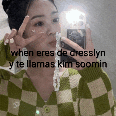 a woman in a green and white checkered sweater is taking a picture of herself in the mirror