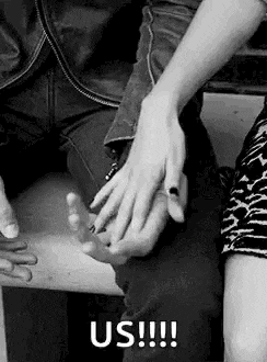 a black and white photo of a man and woman holding hands on a bench .