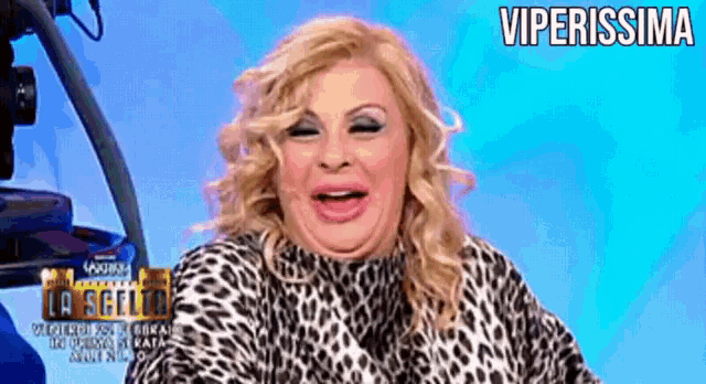 a woman wearing a leopard print shirt is smiling with the words viperissima behind her