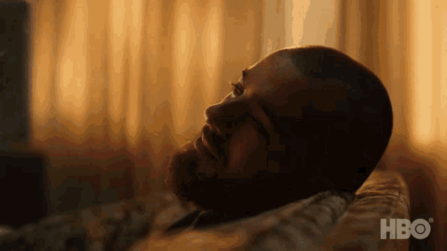 a close up of a man laying on a couch with hbo written on the bottom