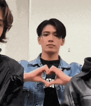 a young man is making a heart shape with his hands .