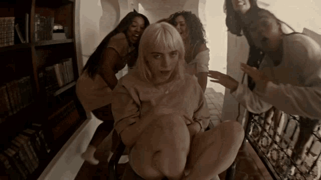 a group of women are standing around a woman in a room