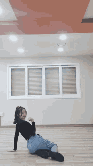 a woman is kneeling on the floor in front of a window with blinds