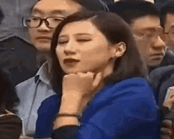 a woman is sitting in a crowd of people with her eyes closed .
