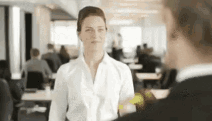 a woman in a white shirt is talking to a man in a room .