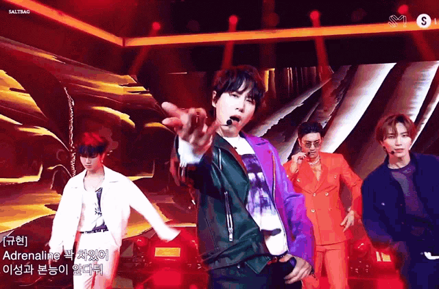 a group of men are performing on a stage and one of them is wearing a purple jacket