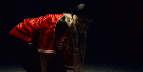 a woman with long blonde hair is wearing a red and black shirt and a black headband .