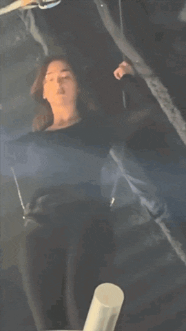 a woman in a black shirt is standing in a dark room with her hands outstretched