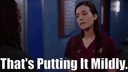 a woman in a scrub top is talking to another woman in a hallway and the words that 's putting it mildly