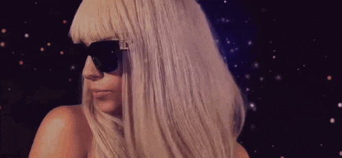 a woman wearing sunglasses and a wig is looking at the camera