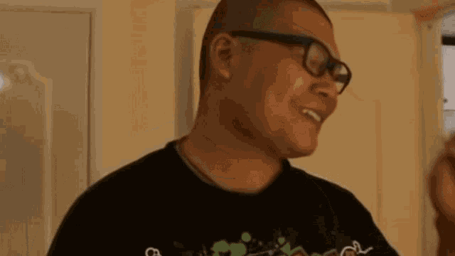 a man wearing glasses and a black shirt with a green design on it