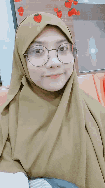 a woman wearing glasses and a hijab with strawberries on her head