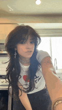 a girl with long hair is taking a selfie in the kitchen