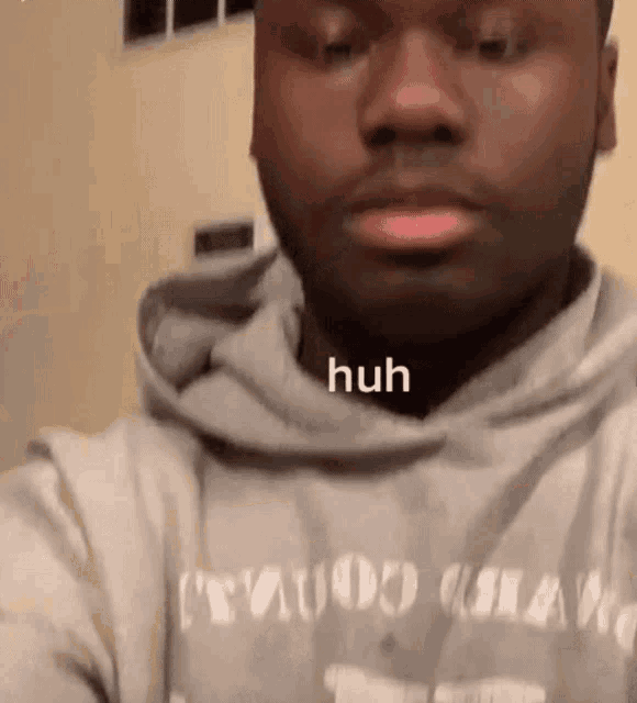 a man in a gray hoodie is making a funny face while taking a selfie .