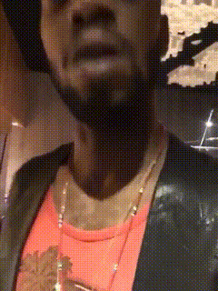a man with a beard wearing a black jacket and a pink shirt