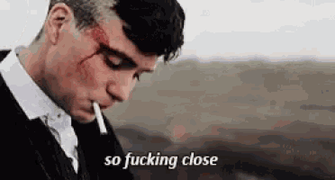 a man with blood on his face is smoking a cigarette with the words so fucking close below him