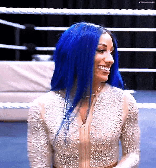 a woman with blue hair is smiling and wearing a white top