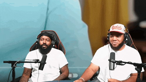 a man wearing a rockets hat sits next to a man wearing headphones