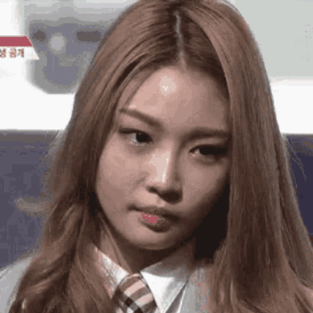 a close up of a woman 's face wearing a tie and a school uniform .
