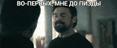 a man with a beard is talking to another man in a room