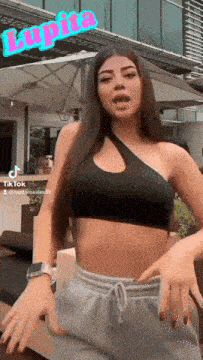 a woman in a black crop top and grey sweatpants is dancing