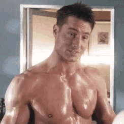 a shirtless man is standing in front of a mirror and looking at himself .