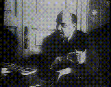a man sitting at a desk with a cat in his lap