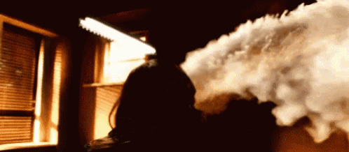 a person is standing in front of a window with smoke coming out of their mouth .