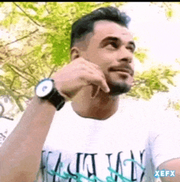 a man with a beard is wearing a watch and a white shirt