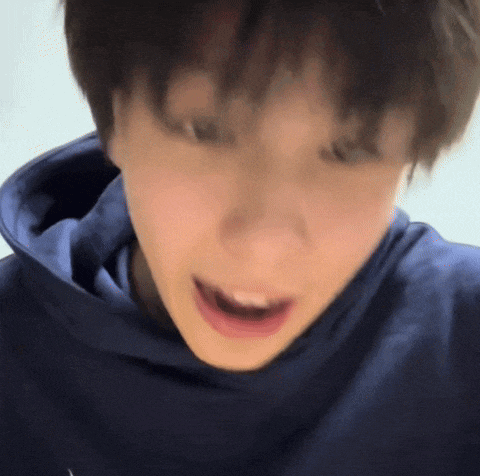 a close up of a person 's face wearing a blue hoodie with their mouth open .