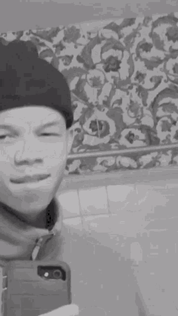 a black and white photo of a man taking a selfie with his tongue hanging out .