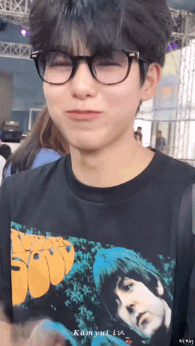 a young man wearing glasses and a black shirt that says beatles