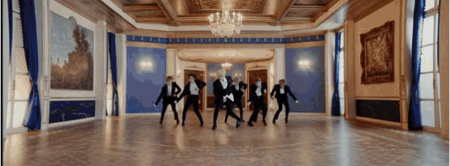 a group of men are dancing in a large room with blue walls .