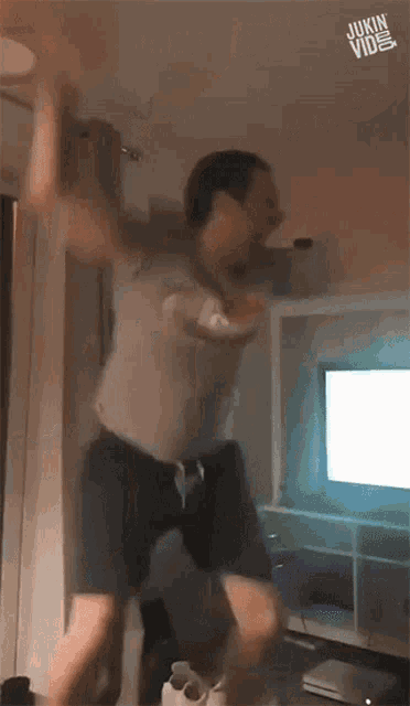 a man is jumping in the air in front of a tv with the words " jukin video " on the bottom
