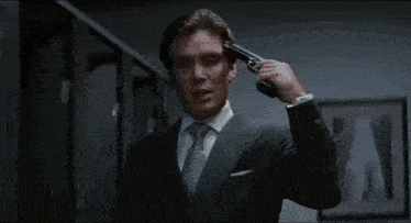 a man in a suit and tie is saluting with his hand to his head .