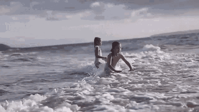a boy and a girl are playing in the ocean .