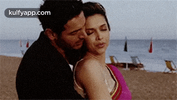 a man and a woman are hugging on a beach .
